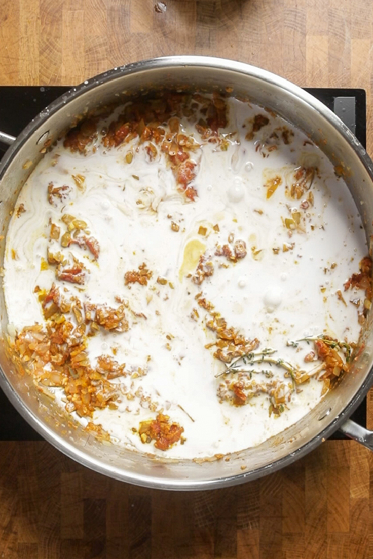 A pot of vegan curry ingredients with coconut milk being cooked. 