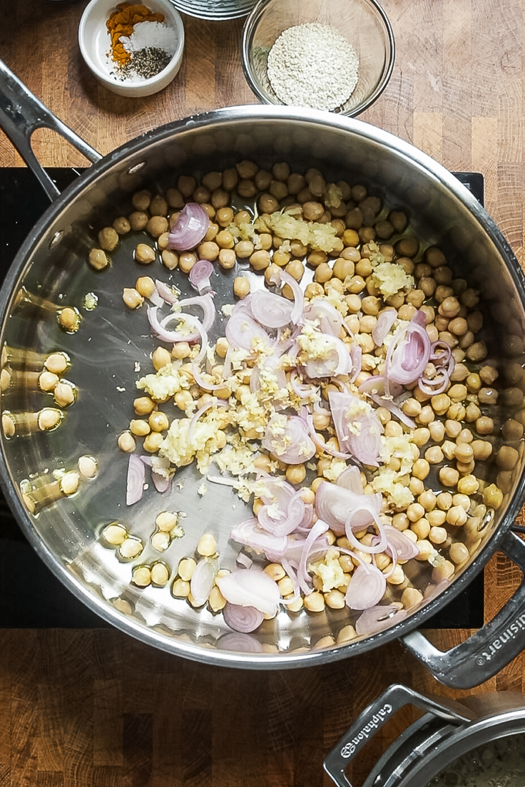 A skillet of chickpeas, shallots, garlic and ginger cooking.