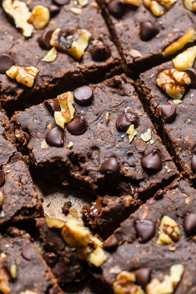 Eine Nahaufnahme veganer Brownies aus schwarzen Bohnen mit Nüssen und Schokoladenstückchen oben drauf.