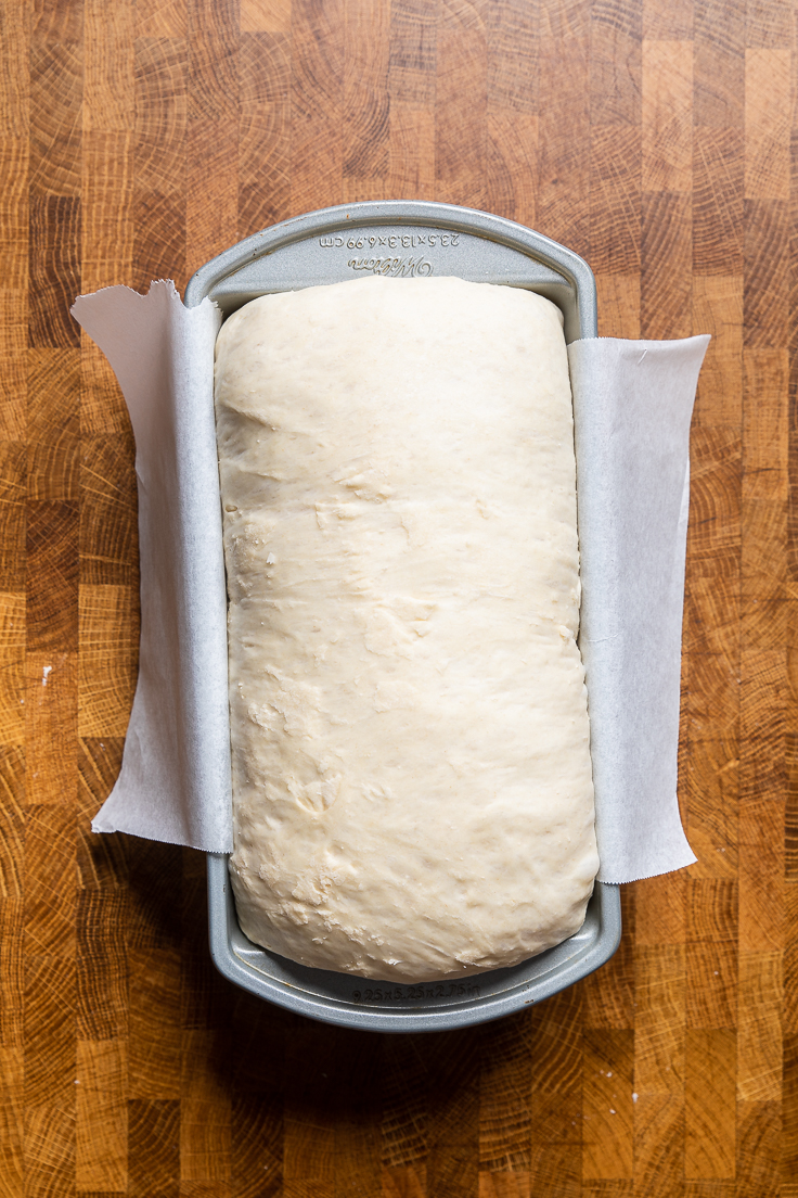 Easy vegan white bread dough risen in a bread pan.