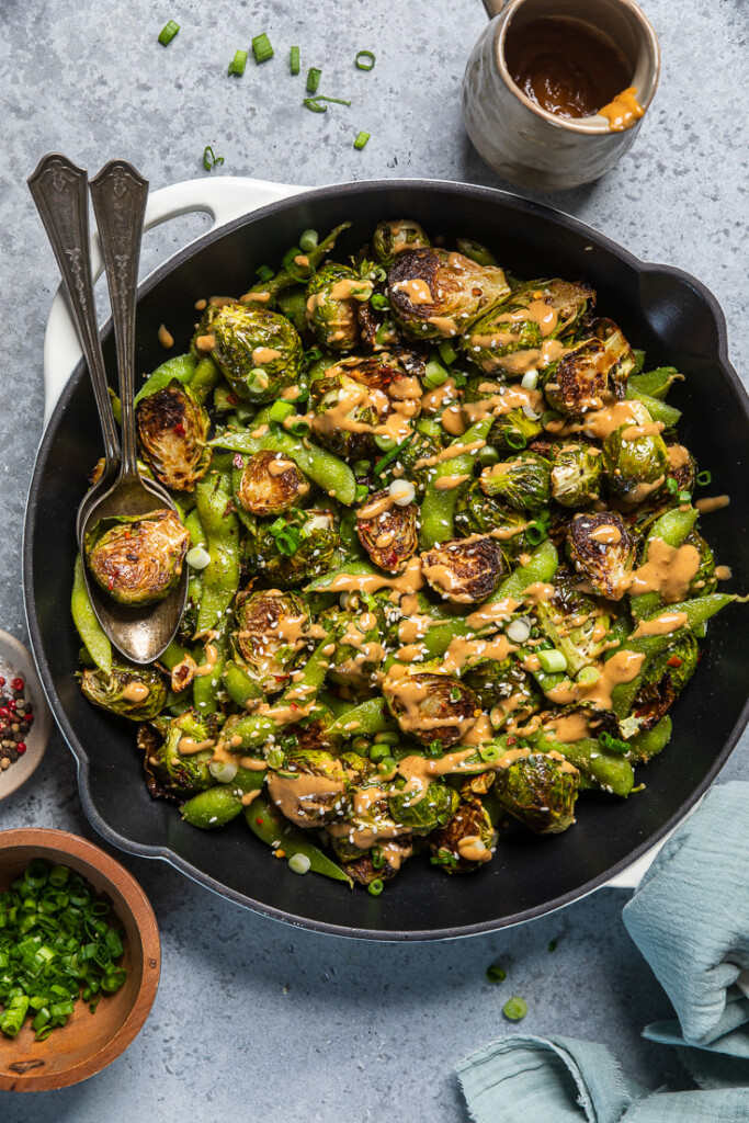 Brussels sprouts, edamame, and spicy peanut sauce in a cast iron dish.