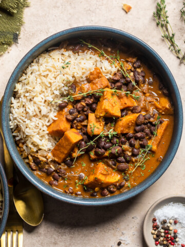 a blue bowl of vegan black bean and sweet potato stew with rice on the left.