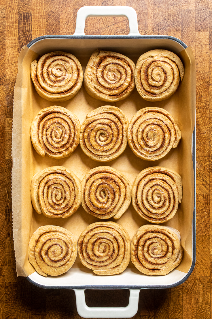 uncooked vegan pumpkin cinnamon rolls slices and laying in a casserole dish. 