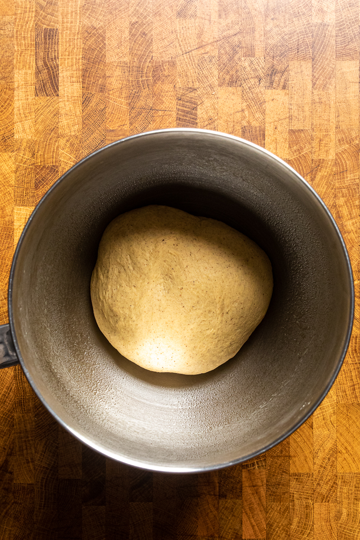 A ball of vegan pumpkin cinnamon roll dough in a bowl.
