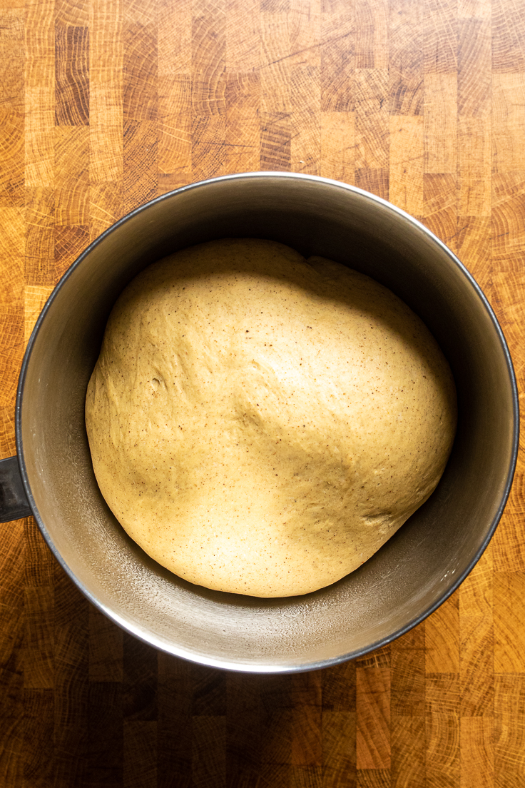 risen dough for vegan pumpkin cinnamon rolls in a bowl.