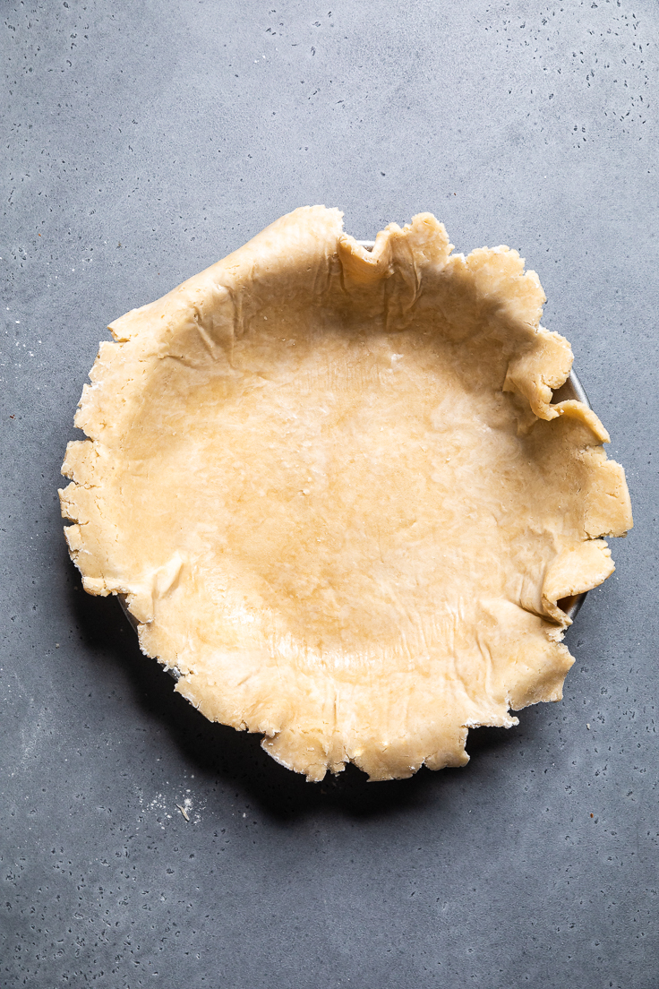 rolled out vegan pie crust laying in a pie dish. 