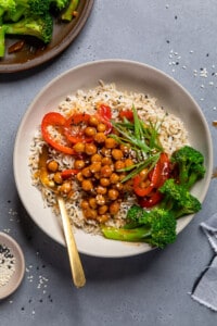 sweet and sour chickpeas with red pepper slices and broccoli over rice in a bowl.