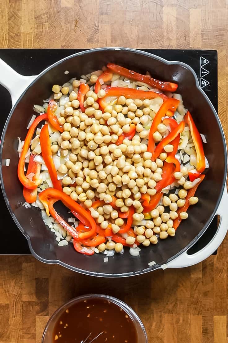 chickpeas, peppers and onions sauting in a skillet.