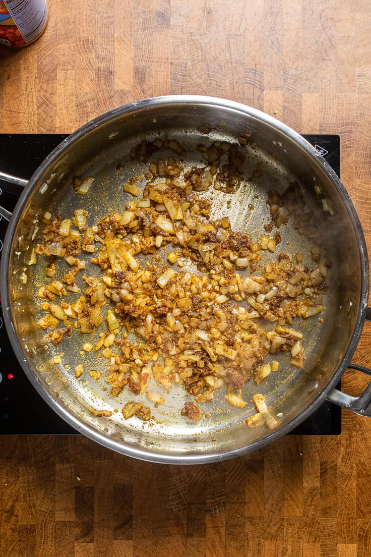 onions, garlic and ginger with spices cooking in a skillet.