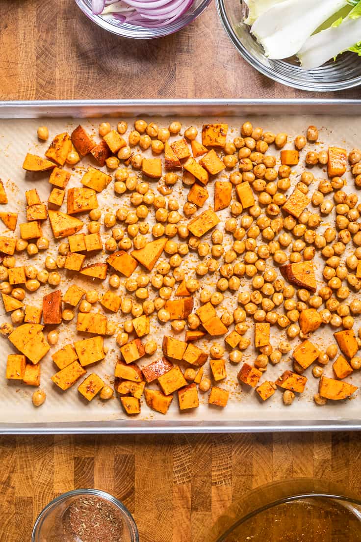 sweet potatoes and chickpeas seasoned on a baking pan uncooked.