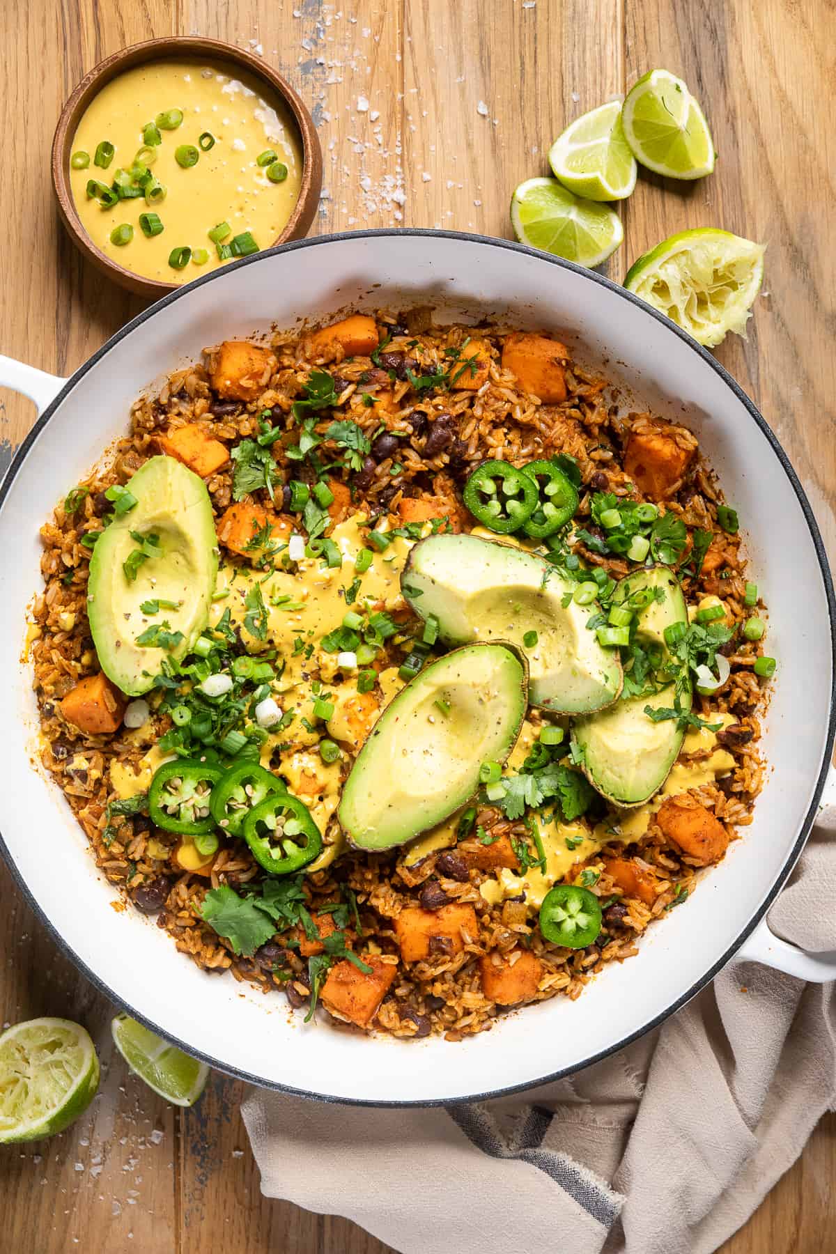 vegan southwest rice in a large white skillet with avocado wedges on top.
