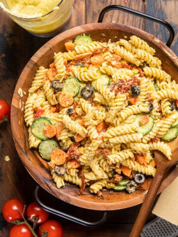 creamy vegan italian pasta salad in a wooden bowl with black handles.