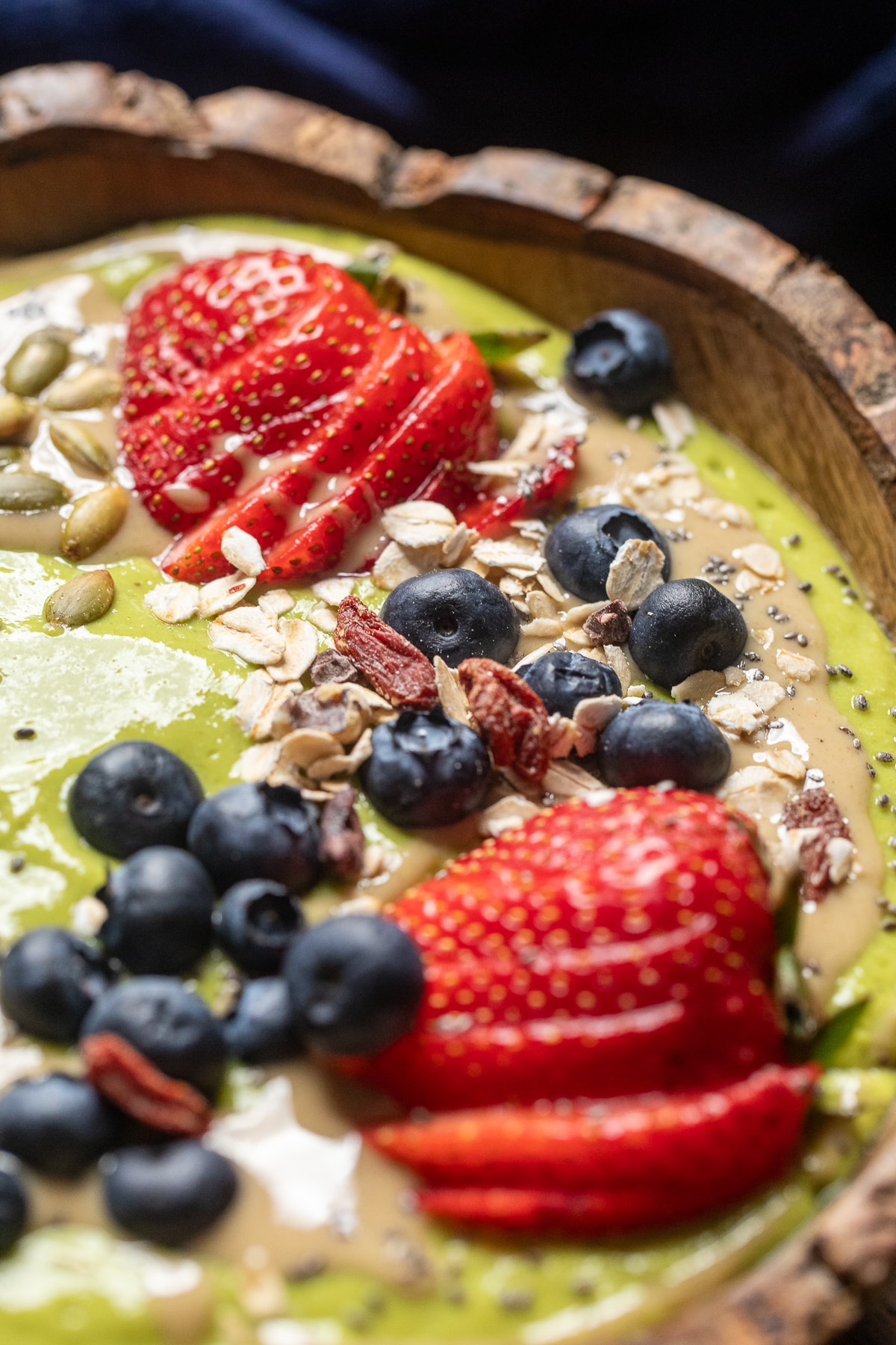 Fresh fruit and granola on top of a green smoothie bowl.