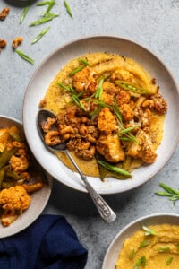 a bowl of creamy miso polenta with roasted cauliflower and snap peas and topped with roasted cashews.