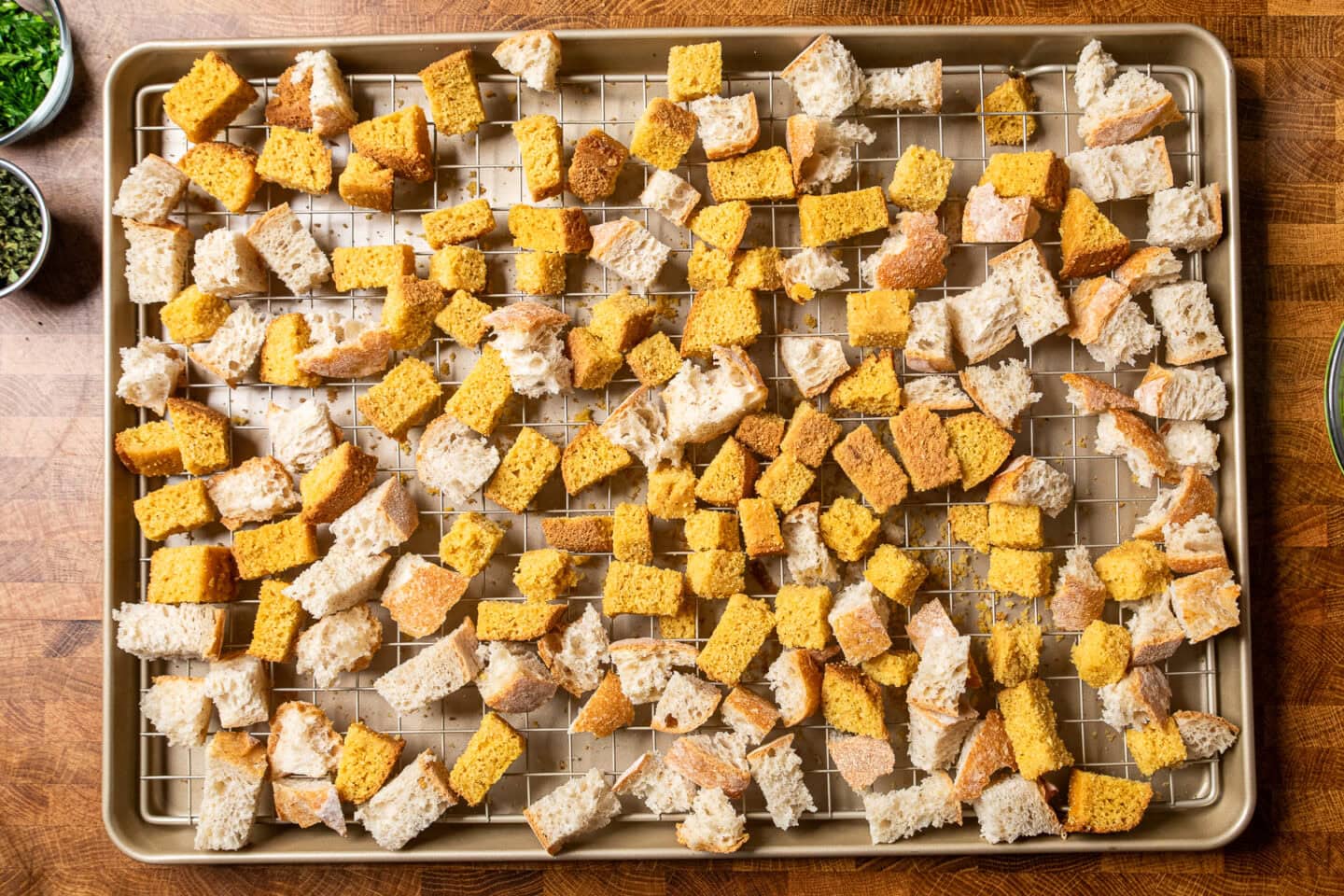 cubes of sourdough and cornbread on a baking rack lined baking sheet to be dried out.