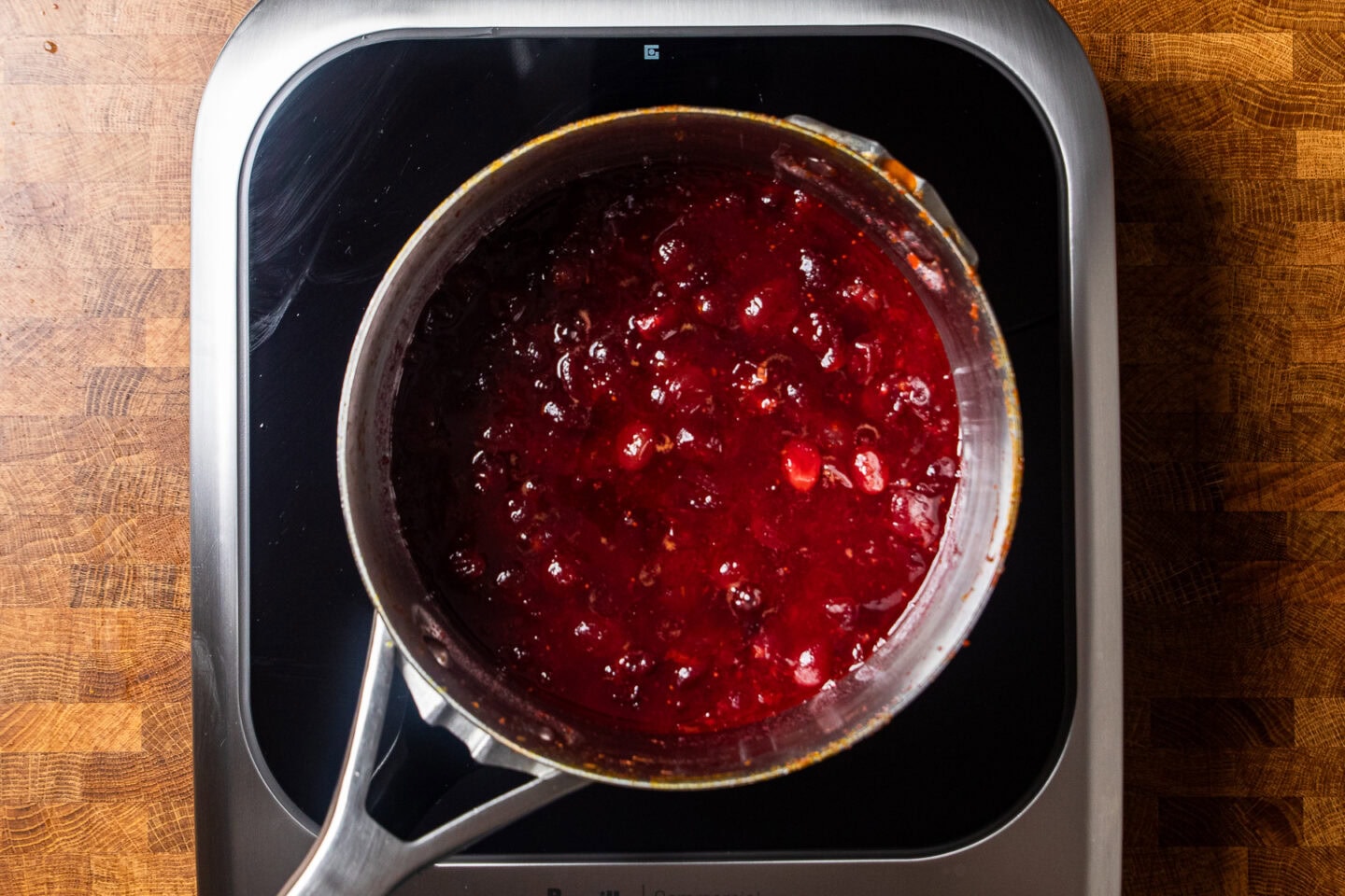 cooked cranberry sauce on a burner in a stainless steel pot.