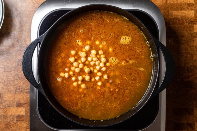 the start of a chickpea soup simmering in liquid in a pot.