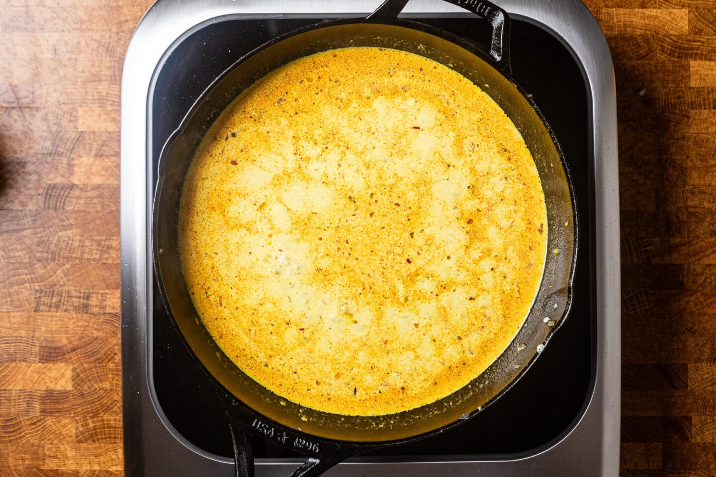 a skillet with a yellow liquid mixture inside cooking.