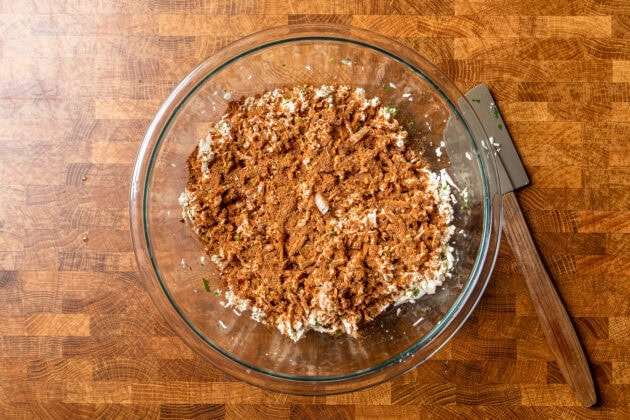 tofu crumbles and seasoning in a large glass bowl before being mixed together.