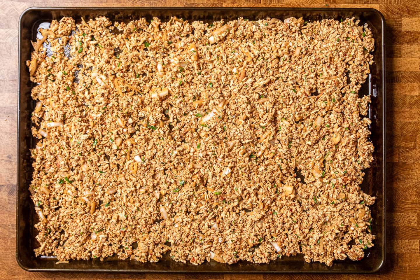 seasoned tofu crumbles on a baking sheet before being baked.