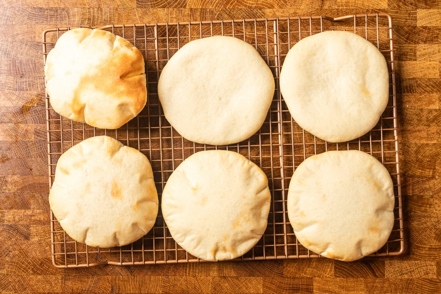 cooked pitas on a wire baking rack.