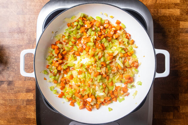 onions, celery, and carrot cooking in a skillet.