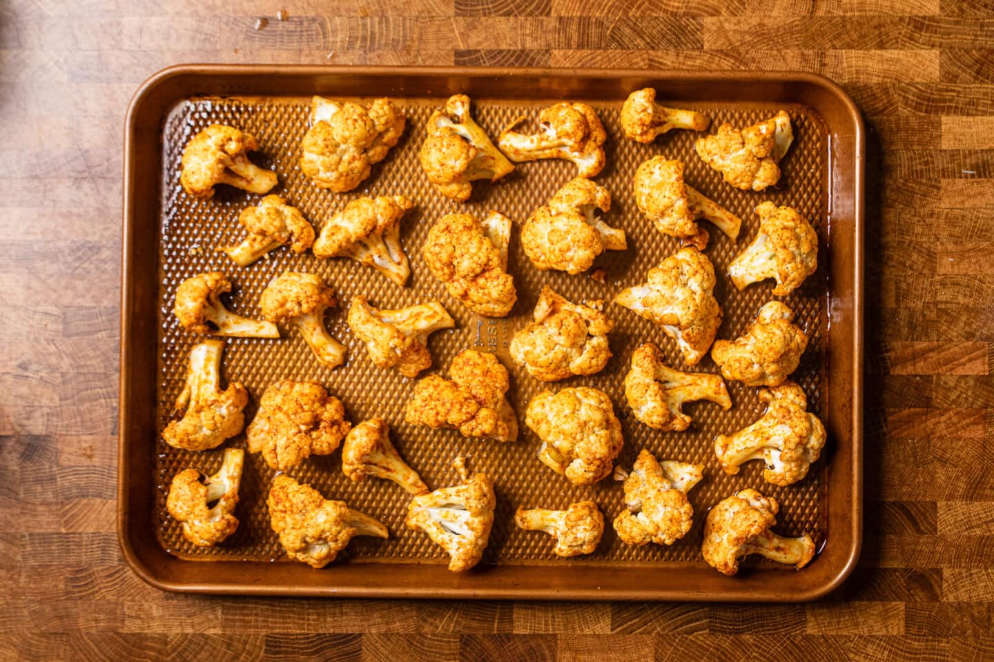 seasoned baked cauliflower on a copper baking tray.