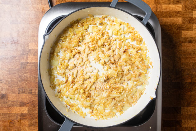 diced onions, garlic, and fresh ginger cooking in a skillet.