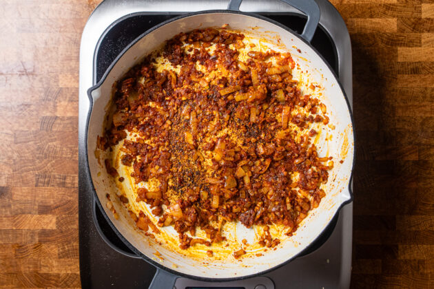 aromatics along with tomato paste and seasonings cooking in a high walled skillet.