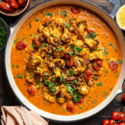 a skillet of roasted cauliflower and lentils with a creamy coconut tomato sauce.