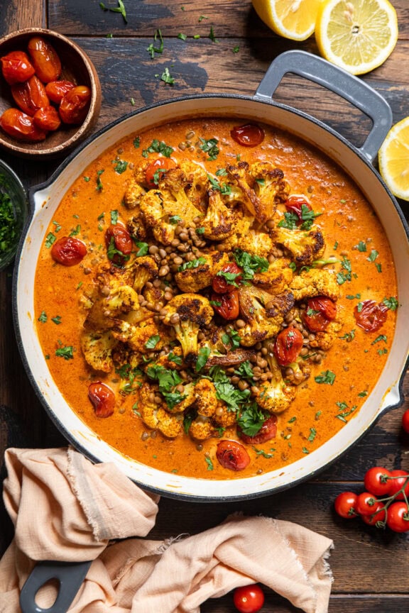 a skillet of roasted cauliflower and lentils with a creamy coconut tomato sauce.