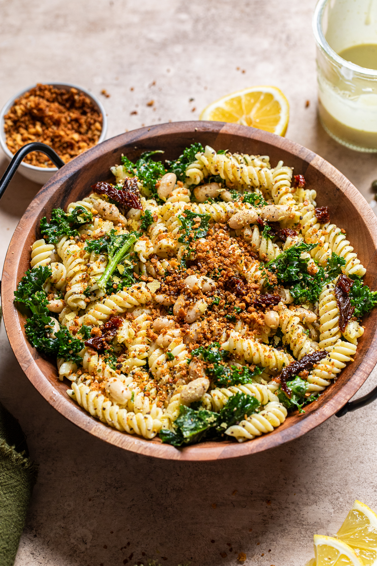 a wooden bowl filled with a garlic and white bean caesar pasta salad.
