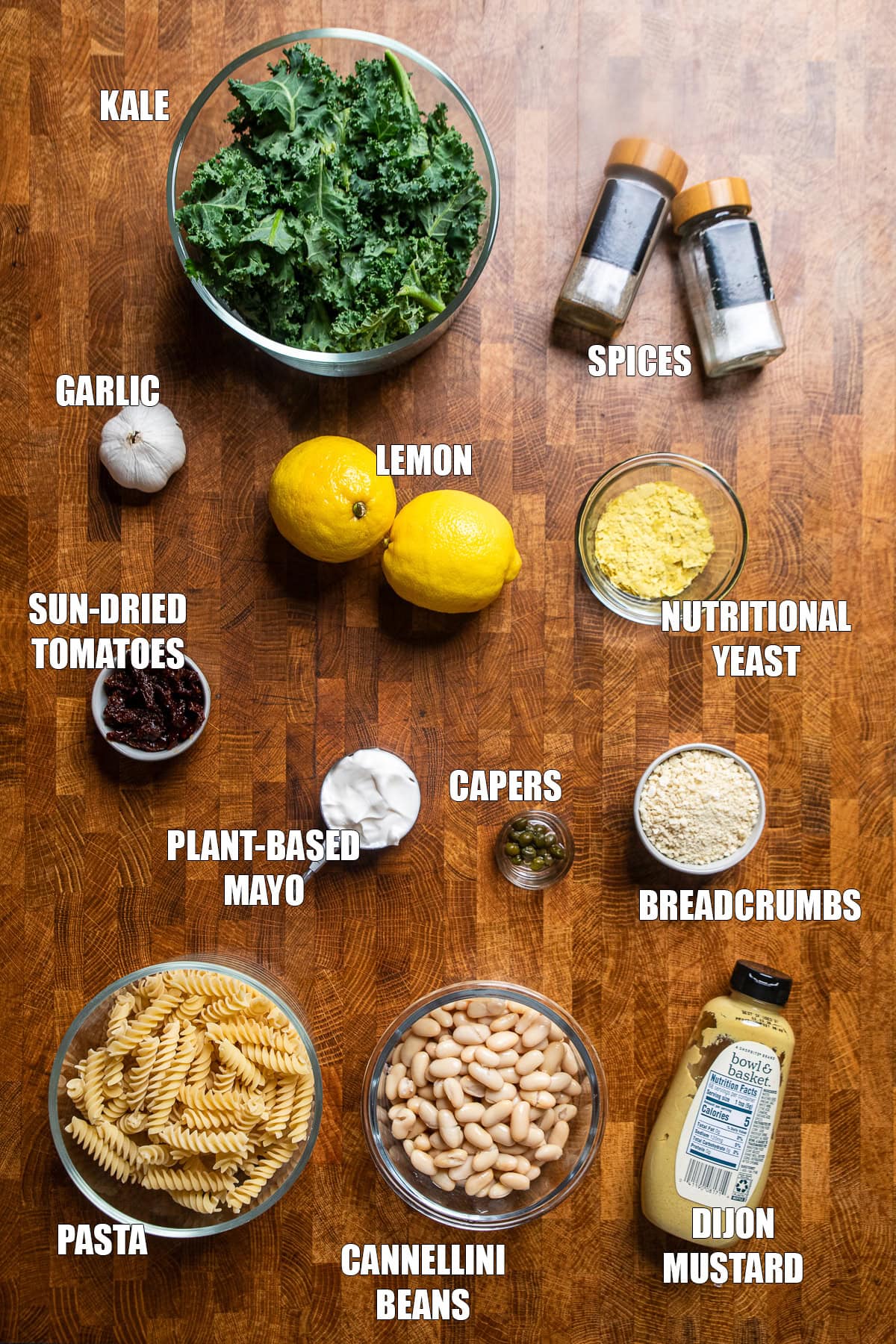 ingredients on a table for a lemon, roasted garlic, and white bean, kale Caesar pasta salad.