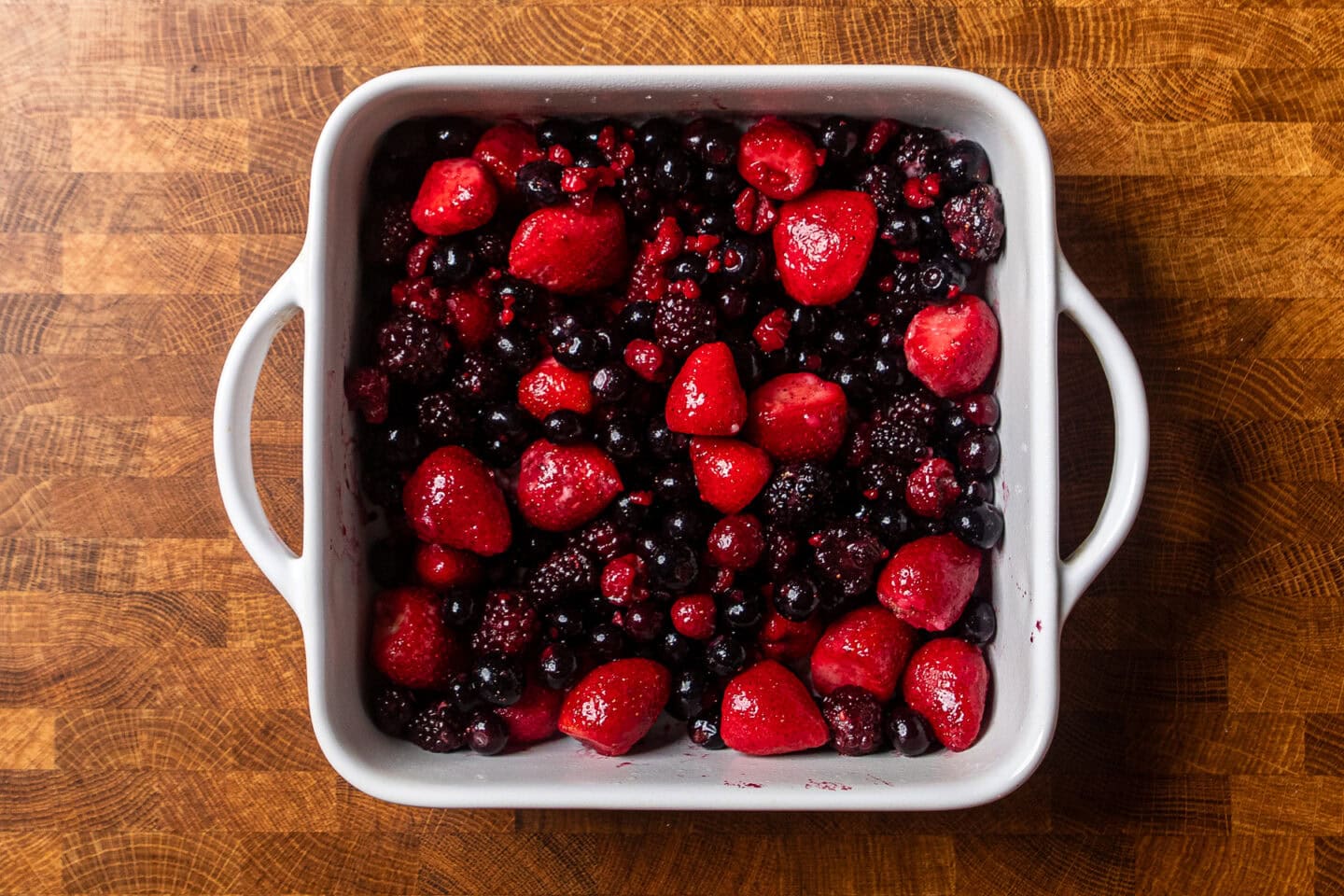 an assortment of mixed berries in a white square baking dish.