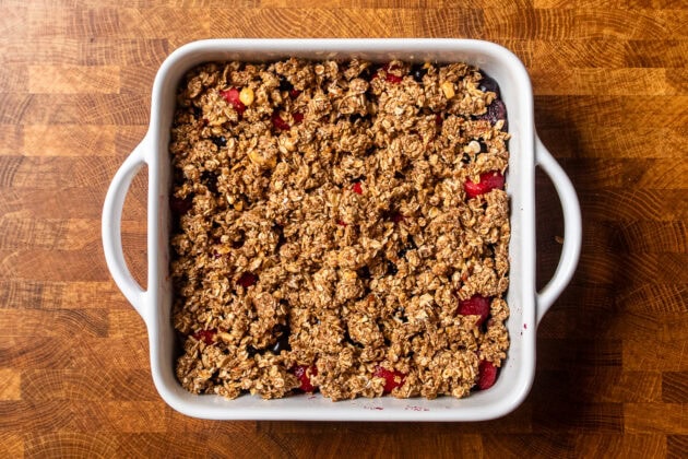 a cooked mixed berry crumble in a white square baking dish.