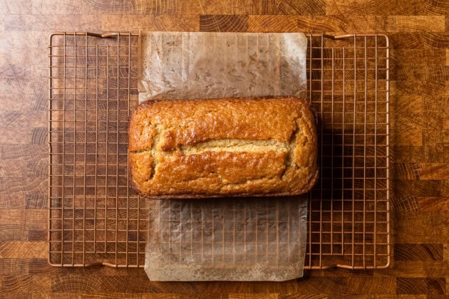 an uncut loaf of vegan pound cake on a copper wire cooling rack.
