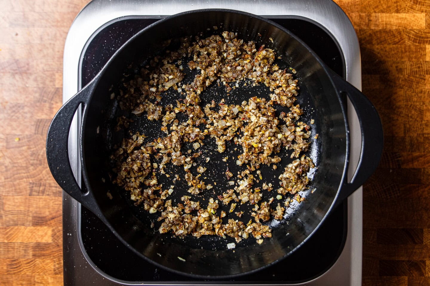 dried spices and onions sauteing in a cast iron skilet.