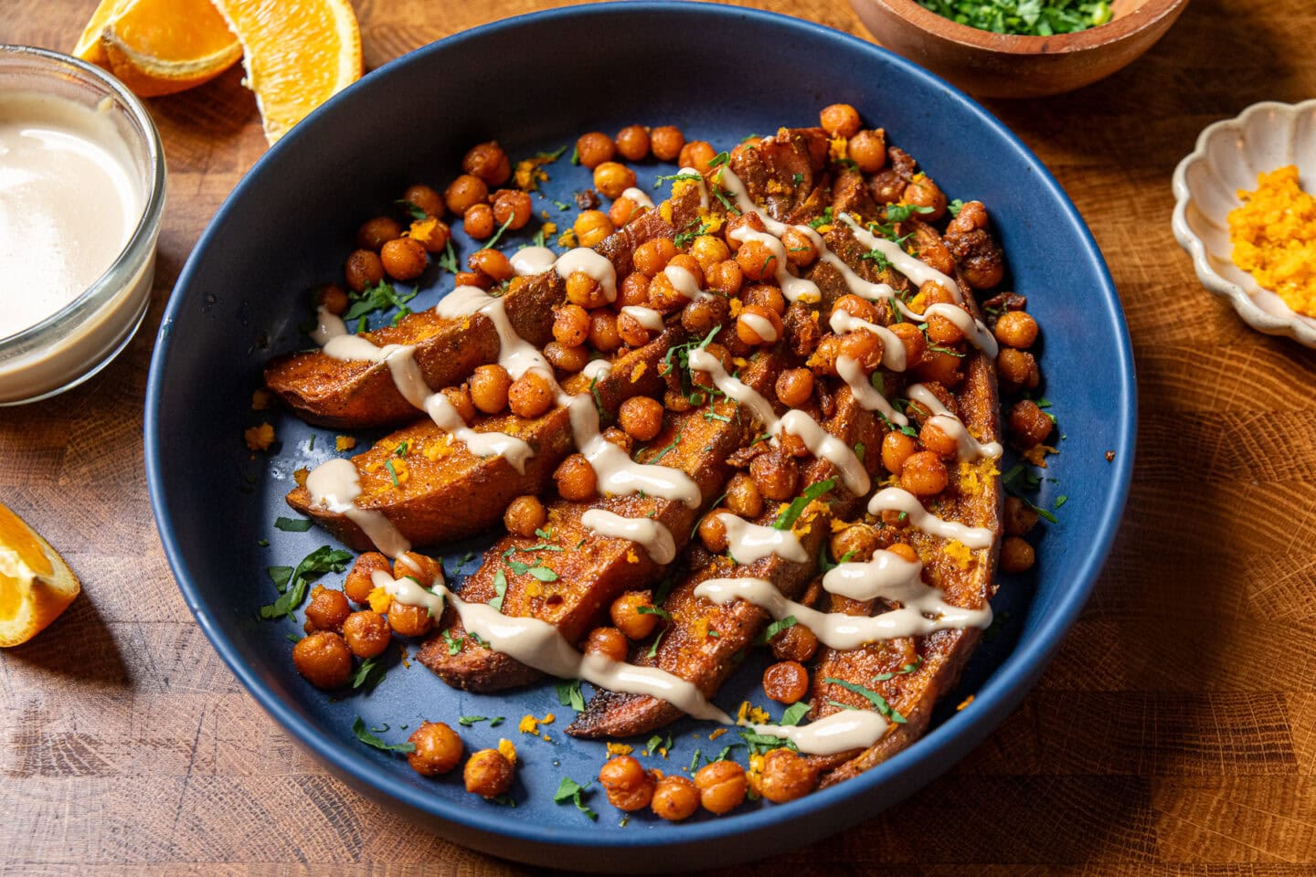tahini butter sauce over roasted sweet potatoes and crispy chickpeas in a blue bowl.