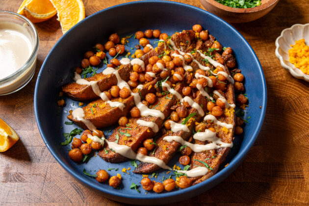 tahini butter sauce over roasted sweet potatoes and crispy chickpeas in a blue bowl.