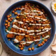 tahini butter sauce over roasted sweet potatoes and crispy chickpeas in a blue bowl.
