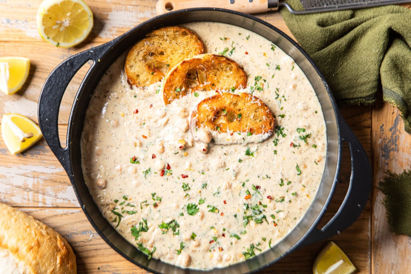 a cast iron pot with garlic lemon pepper creamy chickpeas and slices of toasted bread inside.