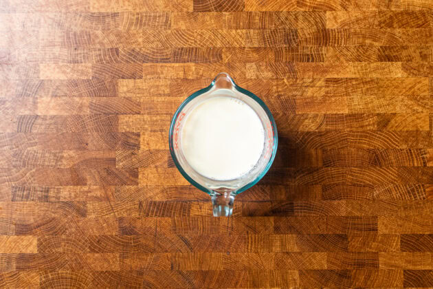 vegan buttermilk in a glass measuring cup sitting on a wooden table.