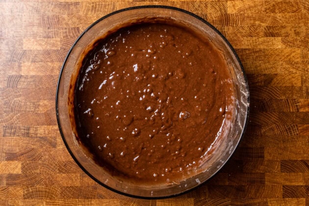 vegan chocolate cake batter in a glass bowl on a table.