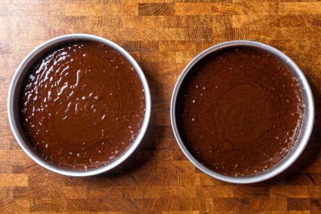 two 8 inch cake pans next to each other filled with vegan chocolate cake batter.