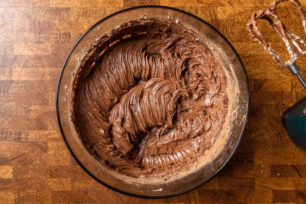 chocolate frosting before adding powdered sugar in a glass bowl.
