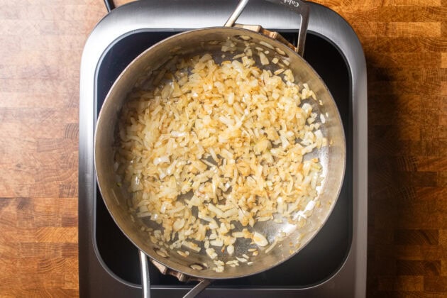 onions caramelizing in a large stainless steel skillet.