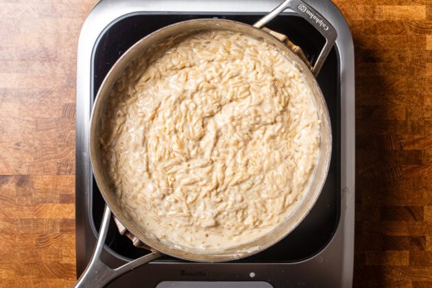 creamy vegan alfredo orzo in a stainless steel skillet.