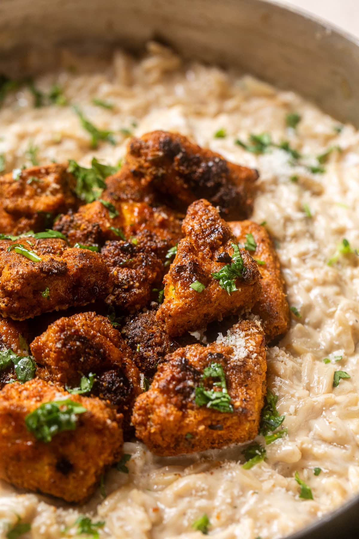close up of vegan chicken alfredo orzo with crispy tofu "chicken" on top.