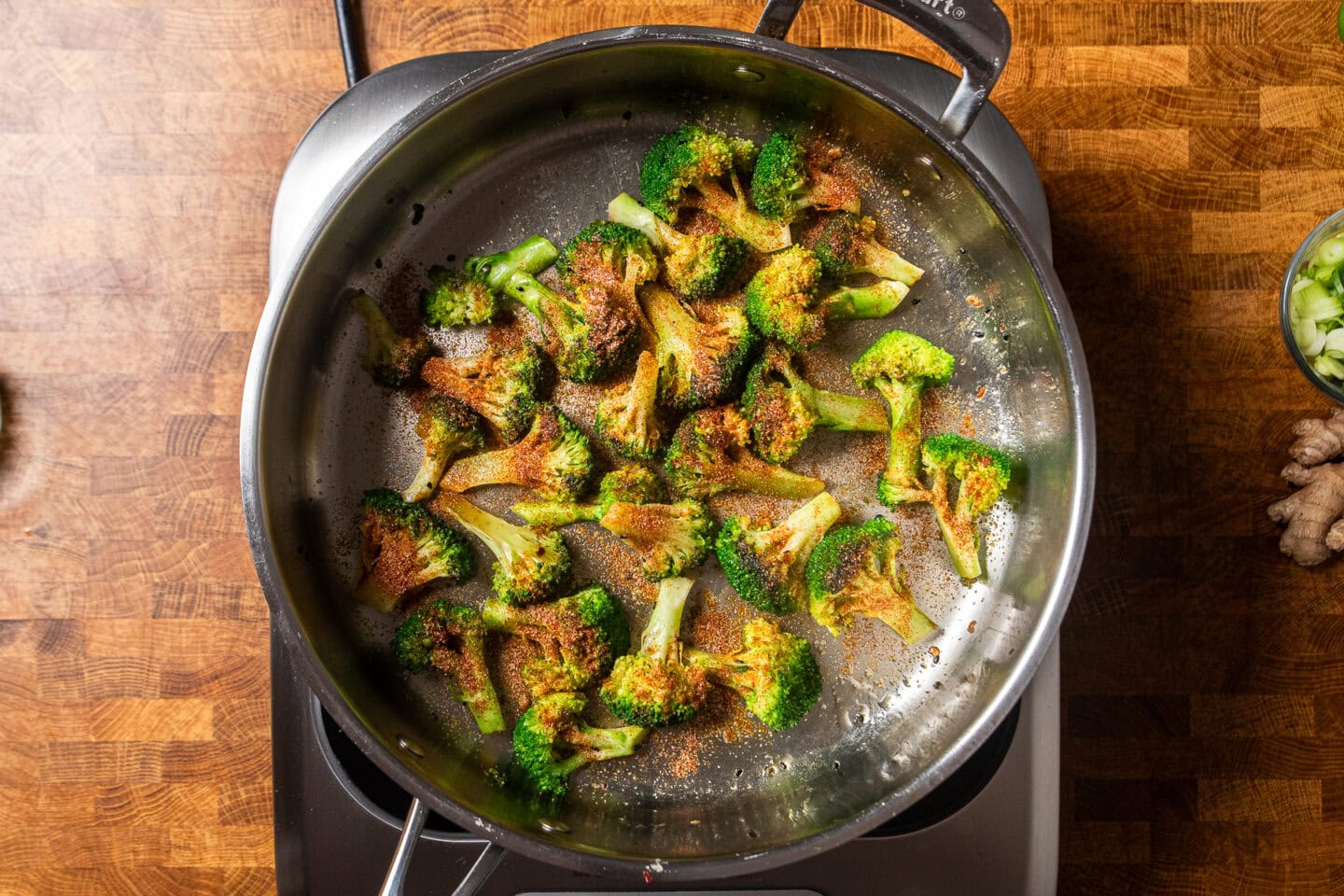 seasoned broccoli sauteing in a stainless steel skillet.