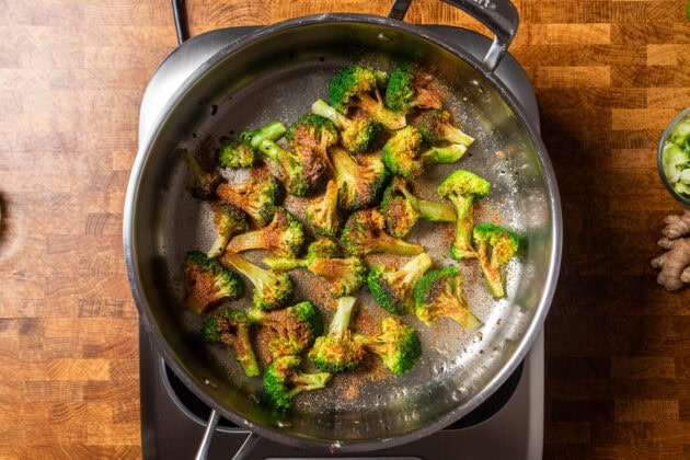 seasoned broccoli sauteing in a stainless steel skillet.
